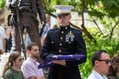 Marine holding a folded American flag at a ceremony
