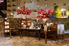 Coffee and water station set out in Alamo Hall Patio with a large floral arrangement on either side