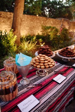 Desserts on a table on a colorful runner with turquoise napkins in a silver cup