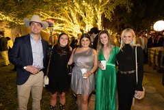 Group of smiling guests in Alamo Gardens in front of trees with white string lights