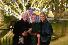 Small group smiling in Alamo Gardens in front of tree with string lights