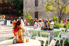Dinner and cocktail tables with festive, colorful linens in Alamo Gardens, border lined with ribbons and sombreros