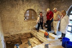 Archaeologist showing an excavation unit to three other people