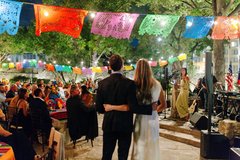 Couple with back to the camera speaking in front of guests seated at tables