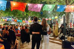 Couple with back to the camera speaking in front of guests seated at tables