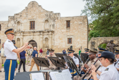 Army conductor leading a group of army musicians seated to the side of Alamo Church