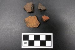 Four Goliad ceramic sherd fragments next to a ruler for size