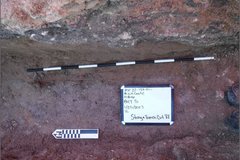 Black and white pole in excavation area next to a marker and a whiteboard