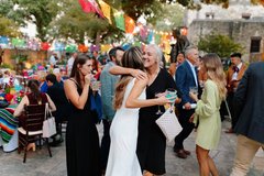 Two women greeting each other with a hug among guests at an event