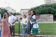 Two women hugging across from the Long Barrack in Alamo Plaza
