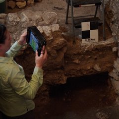 Archaeologist holding a scanner while taking a scan inside an excavation unit