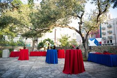 Alamo Hall Patio with cocktail tables in red and blue linens, bar set up, and food table set up