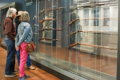 A group of three adults looking at pistols in a display case
