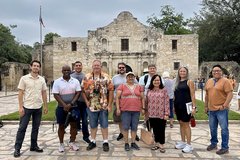 A group of men and women standing in front of Alamo Church