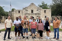 A group of men and women standing in front of Alamo Church