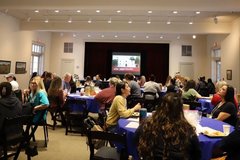 Teacher participants seated at round tables in meeting room