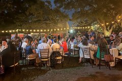 Guests seated at dinner tables in Alamo Gardens with string lights illuminating the event
