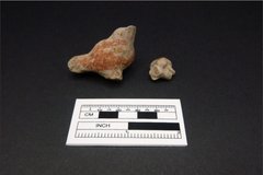 Two burnished figurines next to a ruler