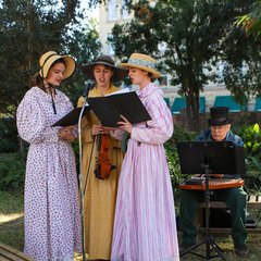 Trio of singers in front of musicians performing in Alamo Gardens