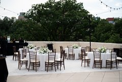 Tables set out with white floral centerpieces and white linens on an outdoor patio