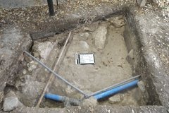Two blue utility pipes at the bottom of an excavation unit
