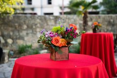 Colorful flowers in a vase placed on a cocktail table with a red linen