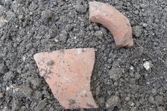 Two pieces of ceramic sherds on a bed of dirt