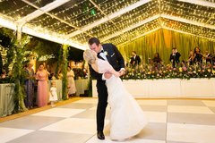 Bride and groom kissing during first dance at wedding on the dance floor under string lighting
