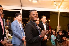 Guests standing listening to remarks at an event