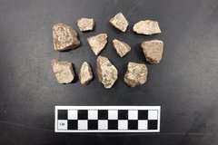 Mortar and plaster fragments next to a ruler for size