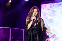 Martina McBride wearing all black singing on stage with purple uplighting