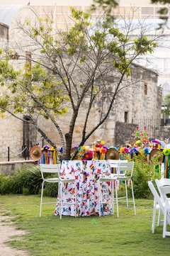 Cocktail table with otomi linen and white chairs outside in a grassy area