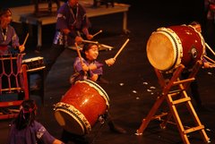 Performer playing a drum with her arms crossed holding drumsticks