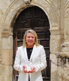 Kate Rogers holding an award outside the door to Alamo Church