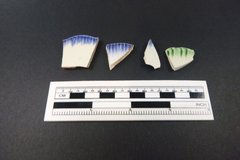 Fragments of ceramic with a color border next to a ruler to show size