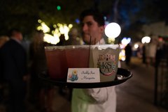 Server holding tray of cocktails with sign that says Prickly Pear Margarita
