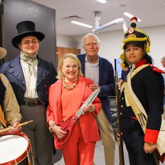 Three living historians and another man next to a woman holding a large pair of scissors
