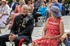 Marine General and his wife smiling at one another while seated during a ceremony
