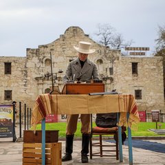 Reenactment of Travis writing letter in front of the Alamo Church