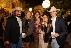 Group of guests in Alamo Gardens at night with illuminated buildings in background
