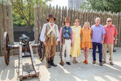 Two living historians standing with other people next to a cannon