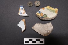 Ceramic fragments and coin artifacts next to a ruler for size