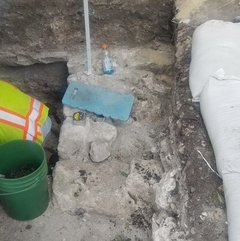 Green bucket at edge of foundation in excavation unit