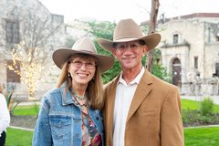 Woman and man wearing cowboy hats smiling at an outdoor event