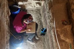 Archaeologist taking notes inside an excavation unit
