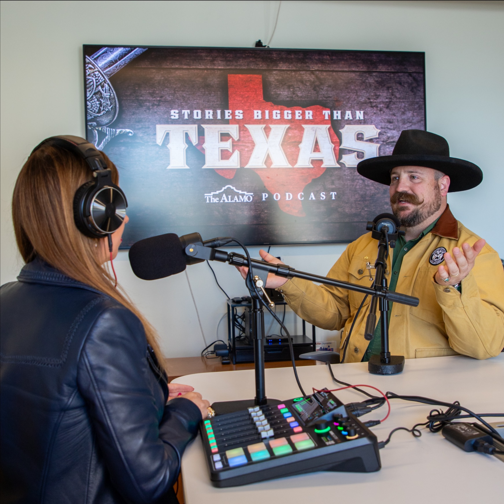 Man in a cowboy hat speaking during an interview with recording equipment on the table
