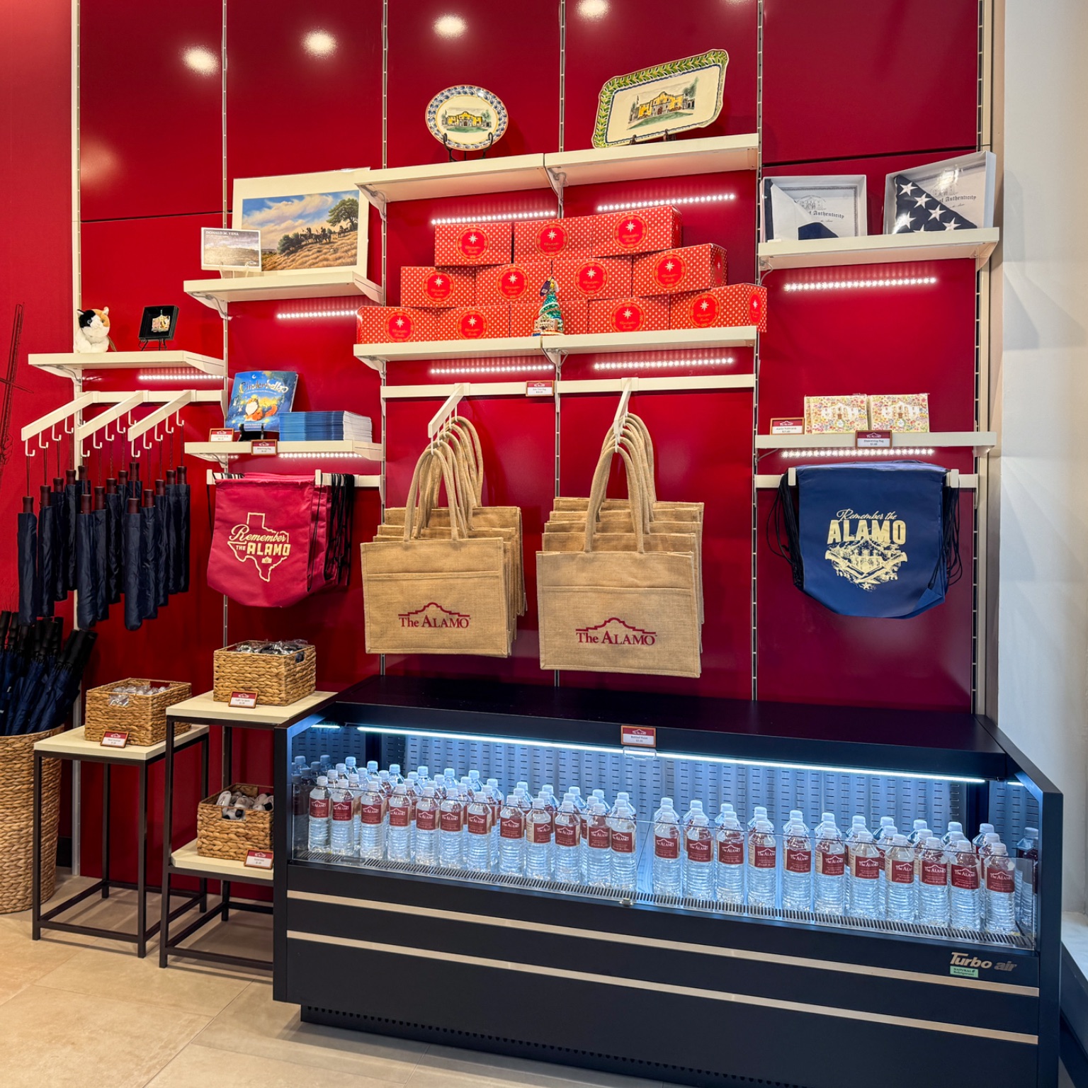 Retail area with bottled waters, bags, ornaments, and displays against a red wall