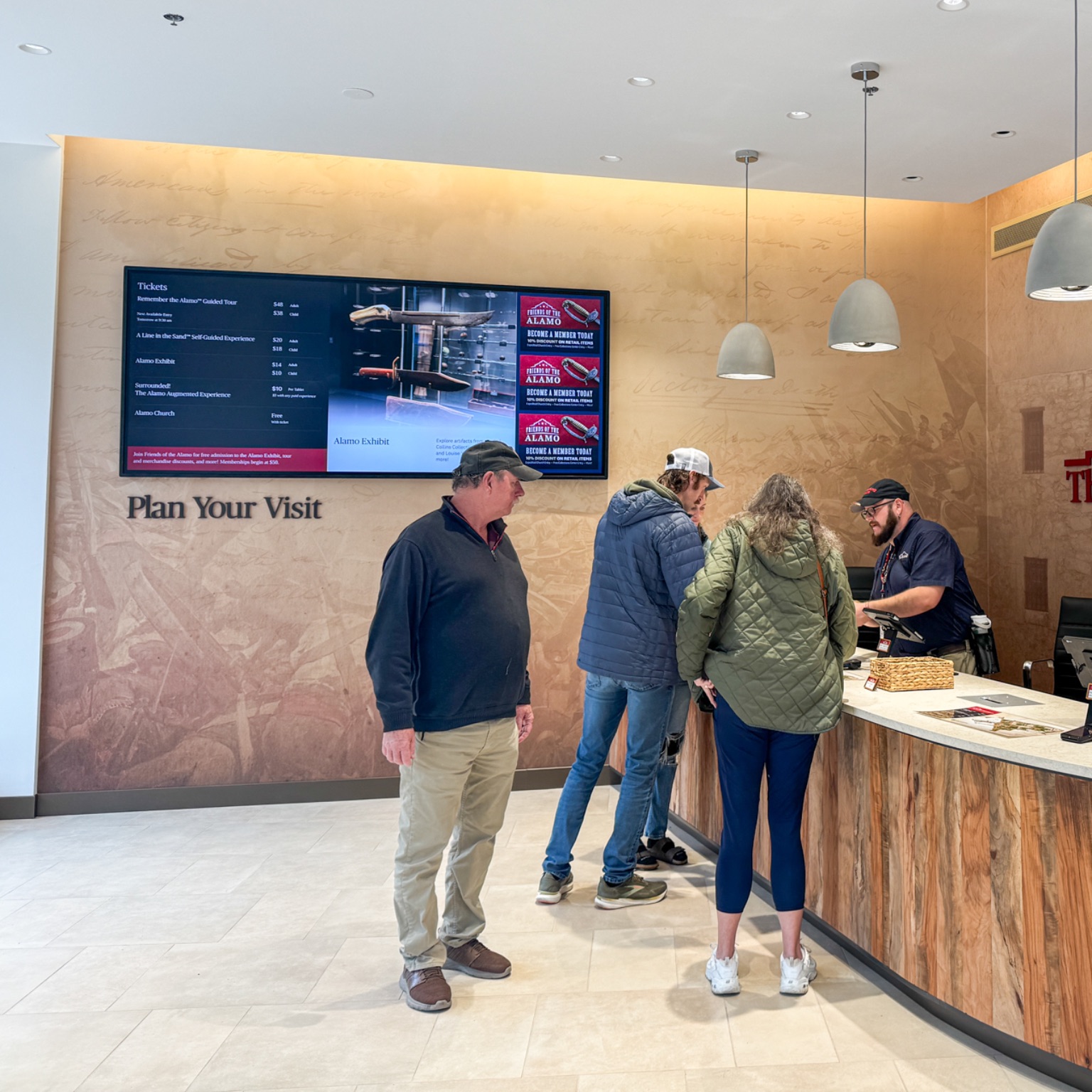 Associate helping guests at a checkout station with another man in line
