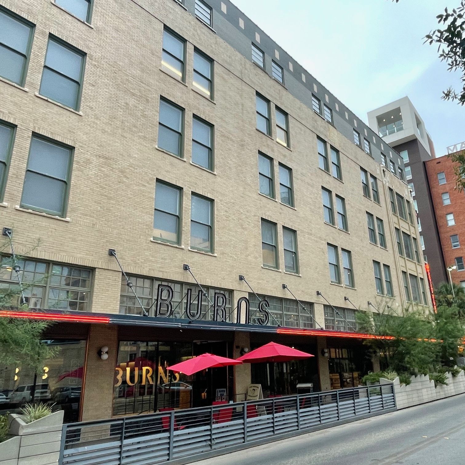 Exterior of a downtown office building with red awnings and red canopies covering outdoor patio tables