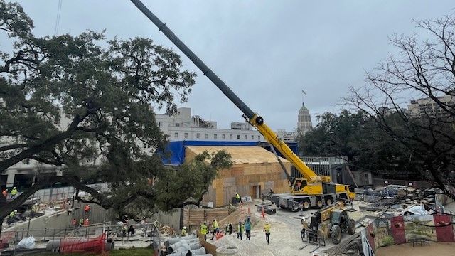 Large yellow crane hovering over a construction site